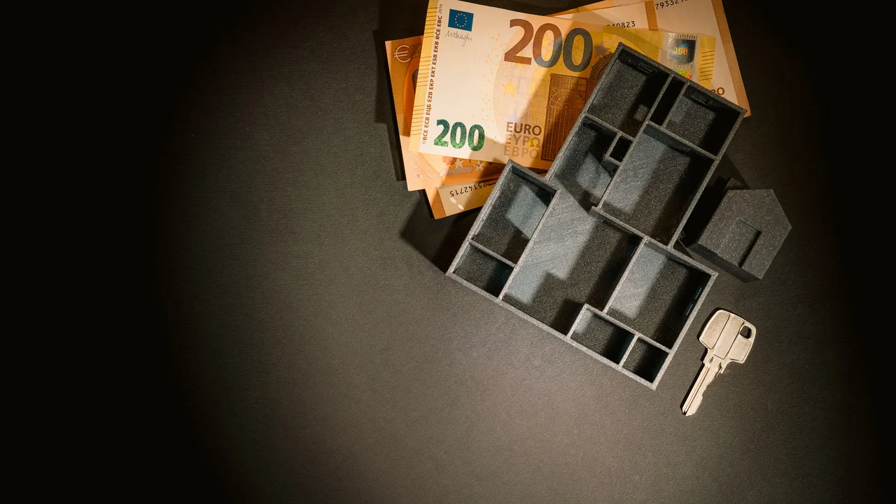 Une maquette de maison, une clé et des billets pour illustrer le patrimoine